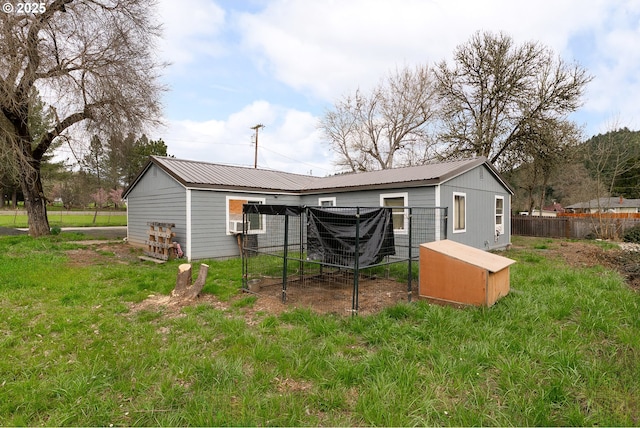 rear view of house with an outbuilding, exterior structure, metal roof, and fence