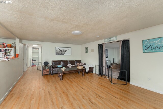 living area featuring baseboards, a textured ceiling, and light wood-style flooring