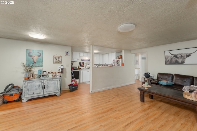 living area featuring light wood-style flooring, a textured ceiling, and baseboards