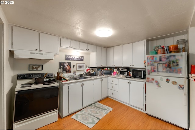 kitchen featuring electric range, under cabinet range hood, freestanding refrigerator, black microwave, and light wood finished floors