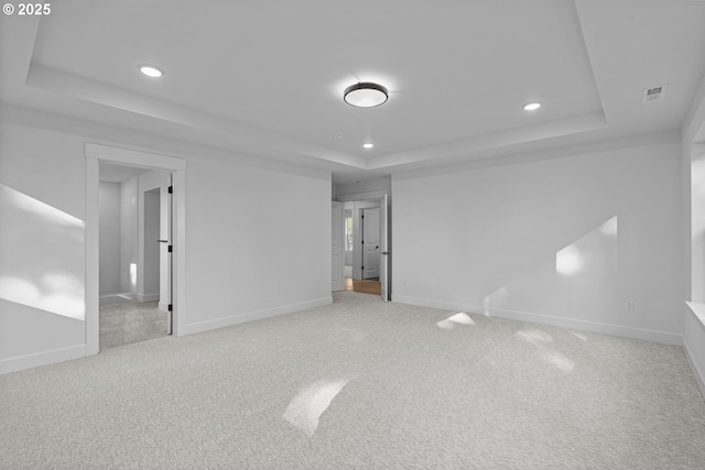 unfurnished bedroom with light carpet and a tray ceiling