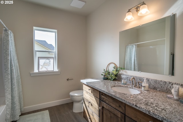 bathroom with vanity, toilet, wood finished floors, and baseboards