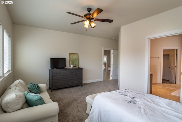 bedroom with light carpet, ceiling fan, a spacious closet, and baseboards