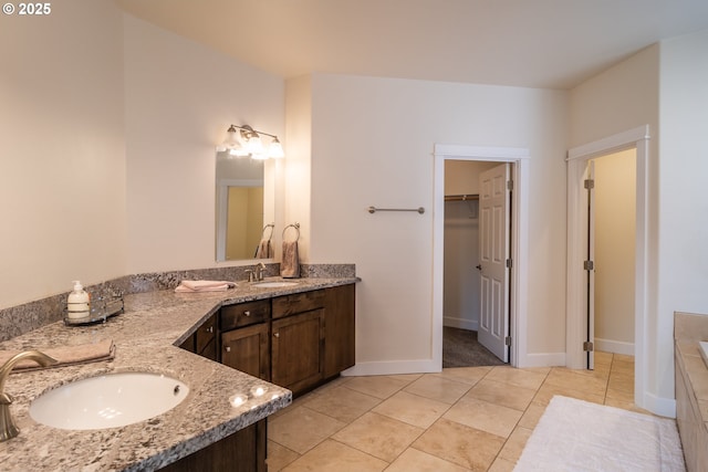 full bathroom with vanity, baseboards, tile patterned flooring, a spacious closet, and a bathtub