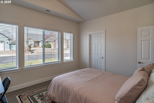 bedroom with visible vents, baseboards, wood finished floors, and vaulted ceiling