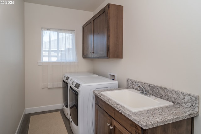 clothes washing area with a sink, baseboards, cabinet space, and washing machine and dryer