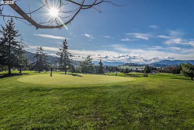 view of home's community featuring a yard, golf course view, and a mountain view