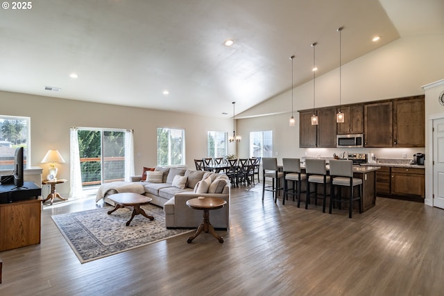 living area with dark wood finished floors, recessed lighting, visible vents, and high vaulted ceiling