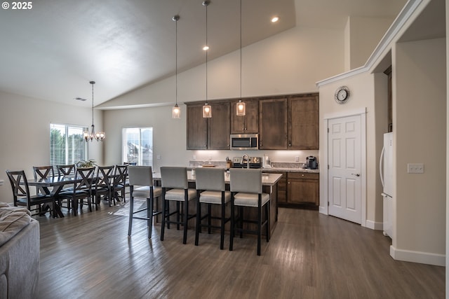 kitchen featuring dark wood-style floors, a breakfast bar, light countertops, stainless steel microwave, and a chandelier