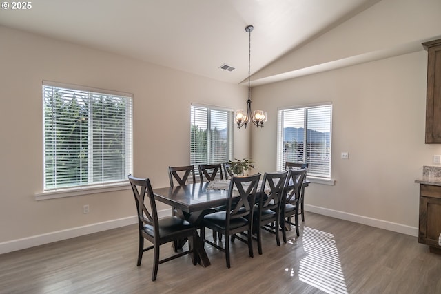 dining area with wood finished floors, visible vents, baseboards, lofted ceiling, and a notable chandelier