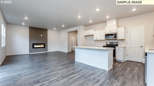 kitchen featuring white cabinetry, appliances with stainless steel finishes, hardwood / wood-style floors, and a kitchen island