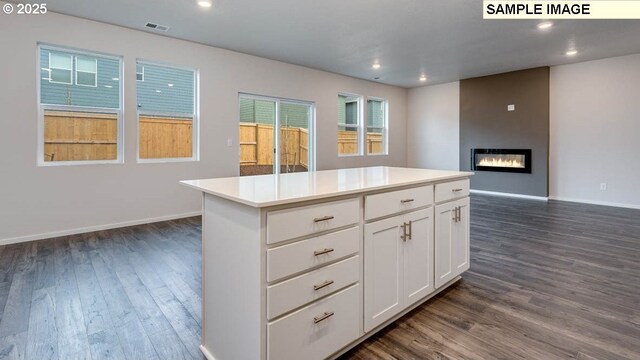 kitchen featuring a center island, dark hardwood / wood-style floors, white cabinetry, and a large fireplace