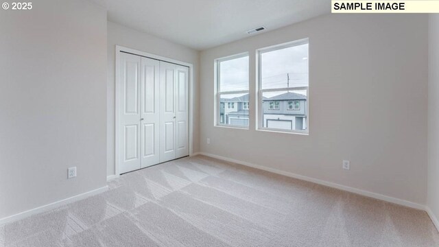 unfurnished bedroom featuring light colored carpet and a closet