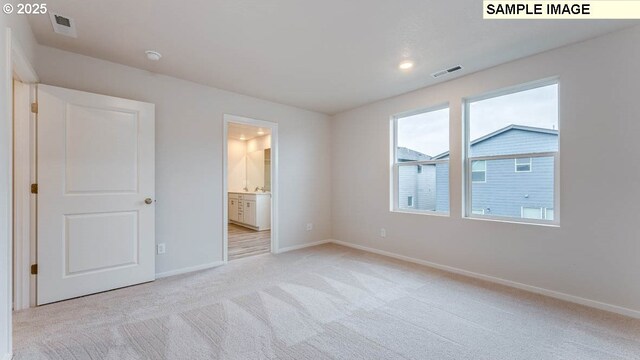 unfurnished bedroom featuring light colored carpet and connected bathroom