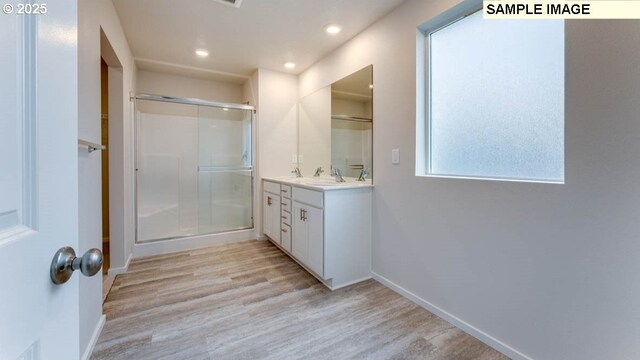 bathroom with wood-type flooring, an enclosed shower, and vanity