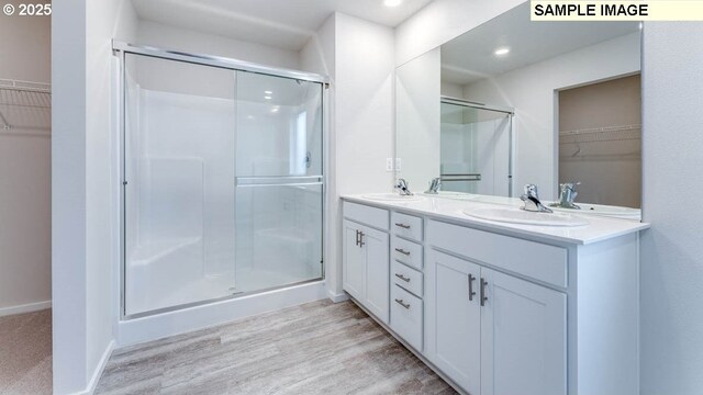 bathroom with vanity, walk in shower, and wood-type flooring