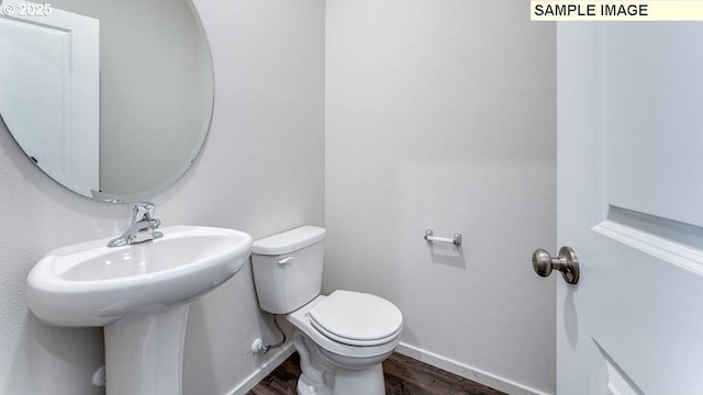 bathroom featuring baseboards, toilet, and wood finished floors