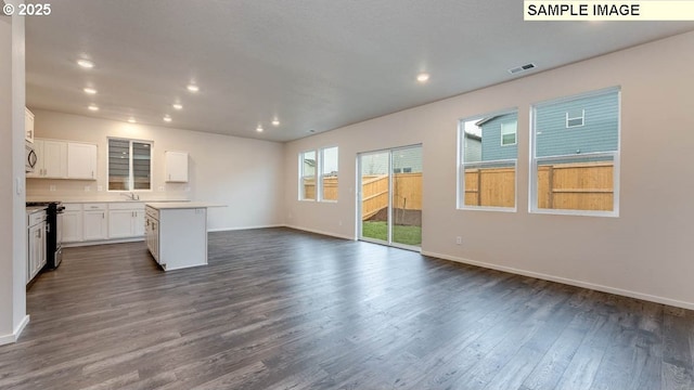 unfurnished living room featuring baseboards, visible vents, dark wood-type flooring, and recessed lighting