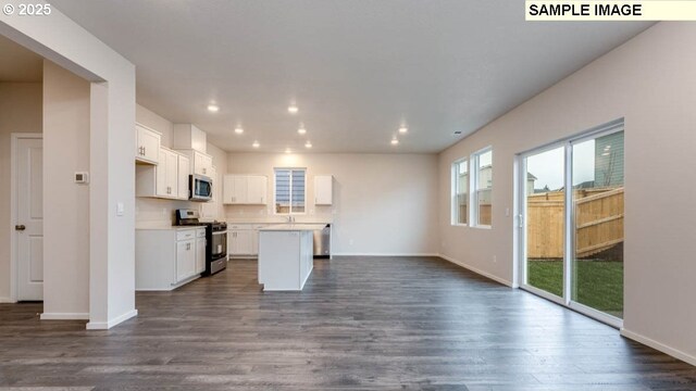 kitchen featuring stainless steel appliances, white cabinetry, a kitchen island, and dark hardwood / wood-style flooring