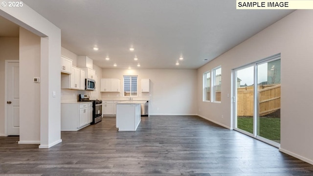 kitchen with open floor plan, appliances with stainless steel finishes, dark wood-style floors, and a center island