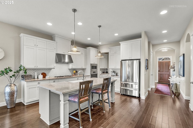 6435 SE Ketchum St, Milwaukie, OR 97267 - kitchen with stainless steel appliances, under cabinet range hood, a sink, arched walkways, and white cabinets