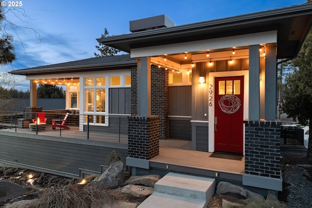 view of exterior entry with a wooden deck, cooling unit, and brick siding