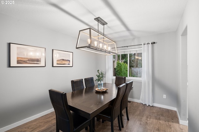 dining space with a notable chandelier, baseboards, and wood finished floors