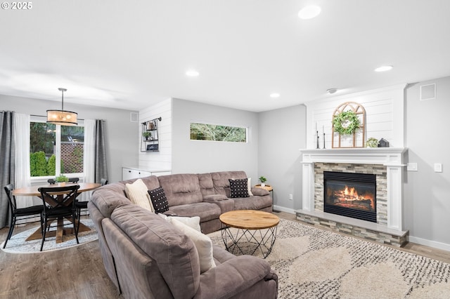 living area featuring a stone fireplace, recessed lighting, wood finished floors, visible vents, and baseboards