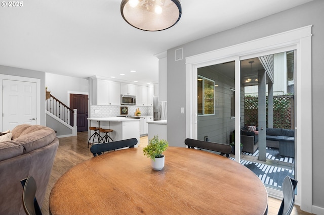 dining area with light wood-style flooring, recessed lighting, visible vents, baseboards, and stairway