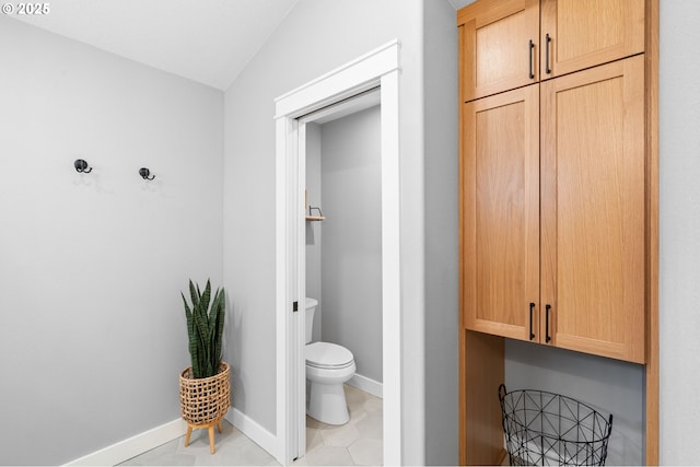 bathroom featuring lofted ceiling, baseboards, toilet, and tile patterned floors