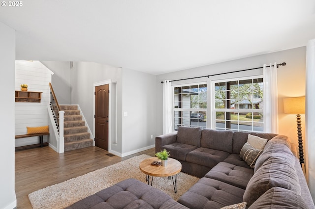 living room featuring stairs, baseboards, and wood finished floors