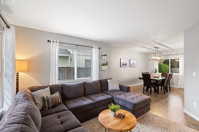 living room featuring baseboards, wood finished floors, and a notable chandelier