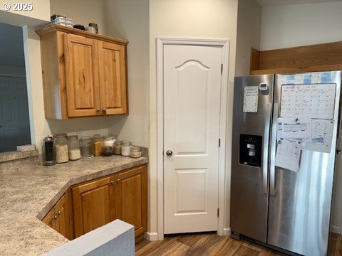 24985 Hunter Ave, Veneta, OR 97487 - kitchen featuring stainless steel fridge, wood finished floors, light countertops, and brown cabinetry