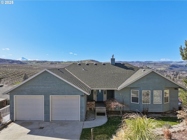 ranch-style home featuring a mountain view, driveway, a garage, and roof with shingles