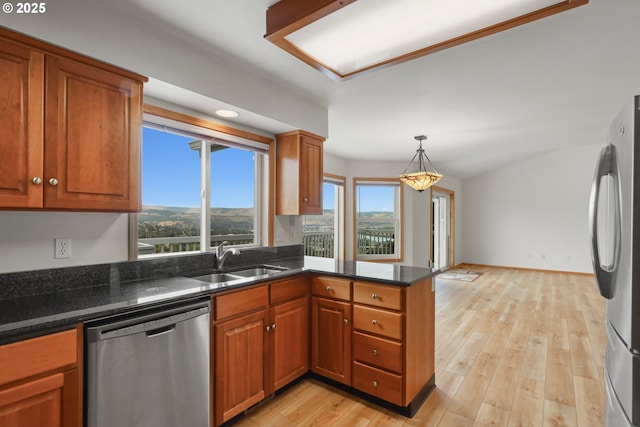 kitchen featuring light wood finished floors, brown cabinetry, appliances with stainless steel finishes, and a sink