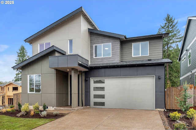 contemporary house featuring an attached garage, concrete driveway, and fence