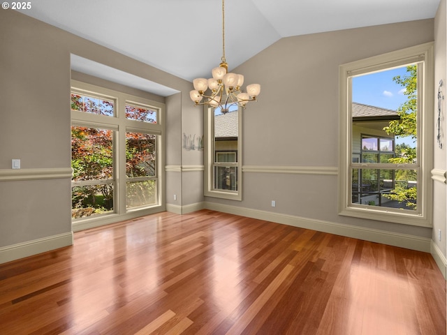 unfurnished dining area featuring hardwood / wood-style flooring, vaulted ceiling, plenty of natural light, and a notable chandelier