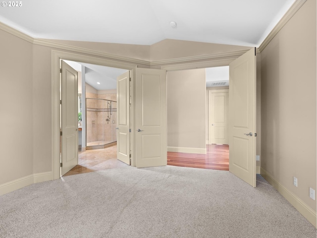 unfurnished bedroom with light carpet, a closet, lofted ceiling, and ornamental molding