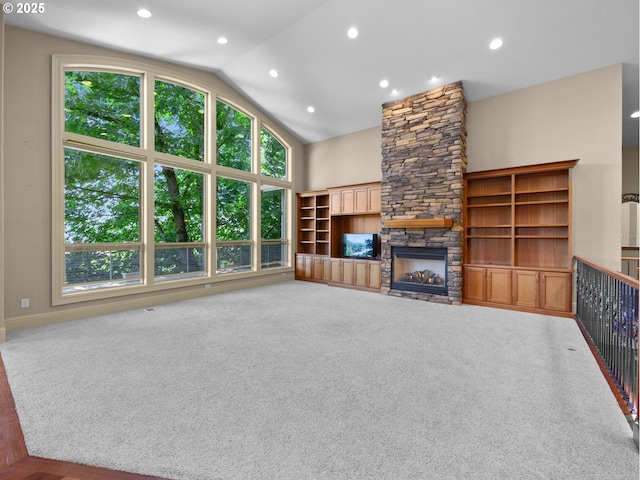 unfurnished living room with a stone fireplace, carpet floors, and high vaulted ceiling