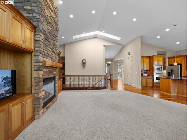 living room featuring light carpet, a stone fireplace, and lofted ceiling