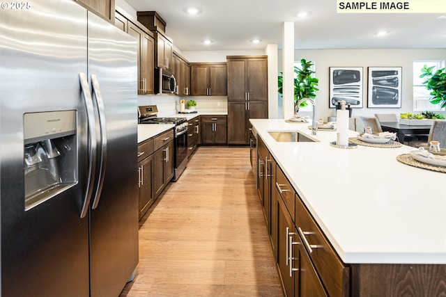 23623 SW Landon Pl, Tualatin, OR 97062 - kitchen with stainless steel appliances, a sink, light wood-style flooring, dark brown cabinetry, and light countertops