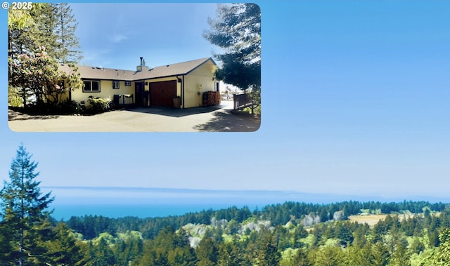 view of yard featuring an attached garage, driveway, and a forest view