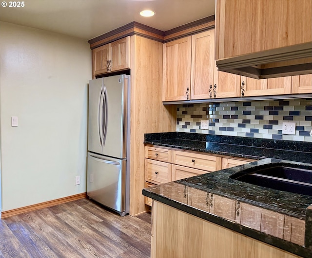 kitchen featuring wood finished floors, freestanding refrigerator, backsplash, and light brown cabinets
