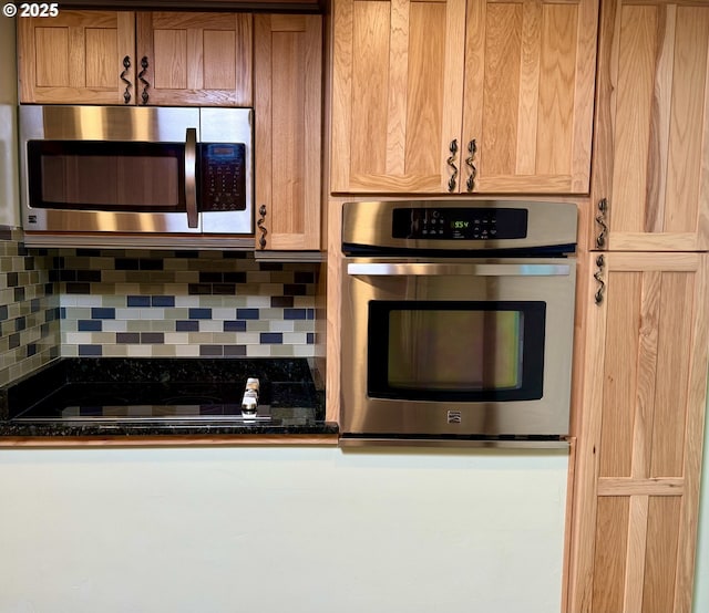 kitchen with appliances with stainless steel finishes, dark countertops, and tasteful backsplash