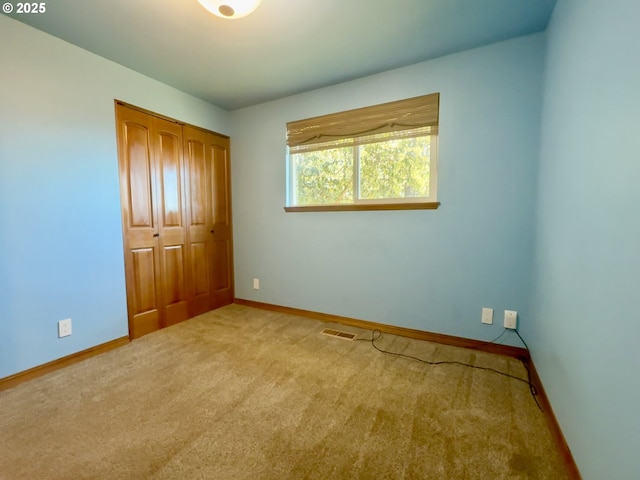 unfurnished bedroom with visible vents, baseboards, carpet floors, and a closet