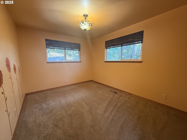 carpeted empty room featuring visible vents
