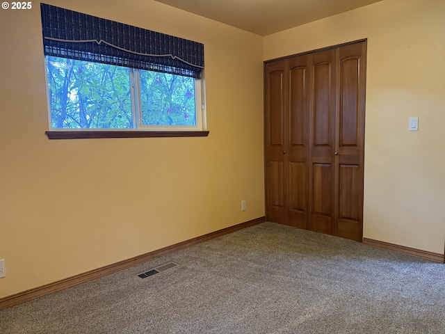 unfurnished bedroom with baseboards, carpet, a closet, and visible vents