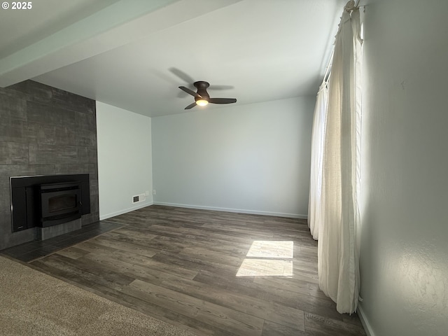 unfurnished living room with ceiling fan, visible vents, baseboards, and dark wood-type flooring