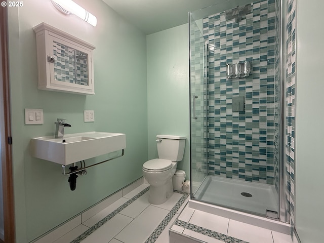 bathroom featuring toilet, tile patterned floors, a sink, and a stall shower