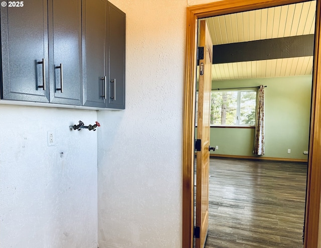 laundry room with cabinet space, baseboards, a textured wall, and wood finished floors